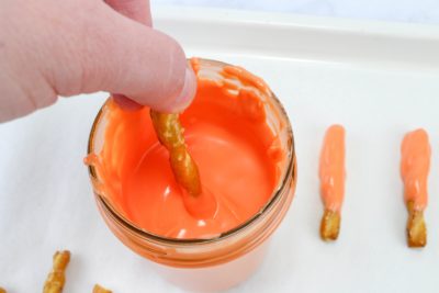 Dipping carrot into orange candy melts