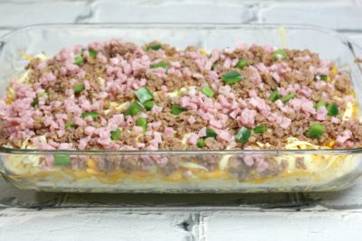 Adding the cheeses, ham and onion on top of the potatoes.
