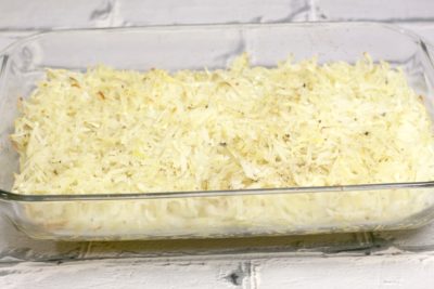 Pouring hash browns into a 9x13-inch baking dish.