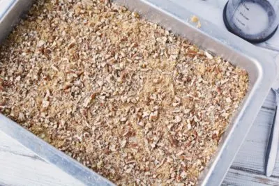 Spreading pecans and brown sugar over top of Fruit Cocktail Cake Spreading pecans and brown sugar over top of Fruit Cocktail Cake