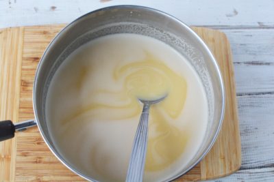 Stirring butter, sugar and evaporated milk together.