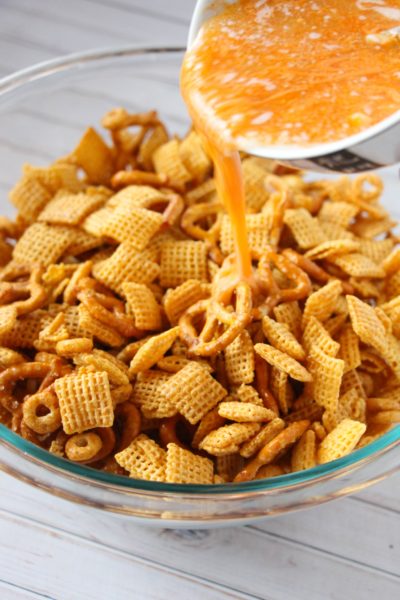 Pouring butter and hot sauce over snack mix