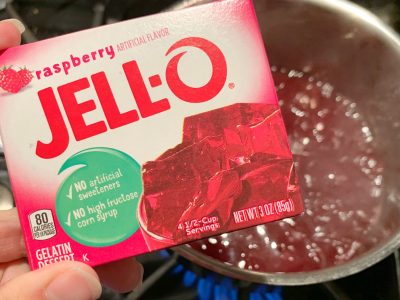 Adding raspberry gelatin to the juice mixture