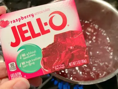 Adding raspberry gelatin to the juice mixture