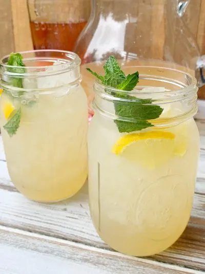 Adding lemon wedges and mint to finish bourbon spiked lemonade cocktail