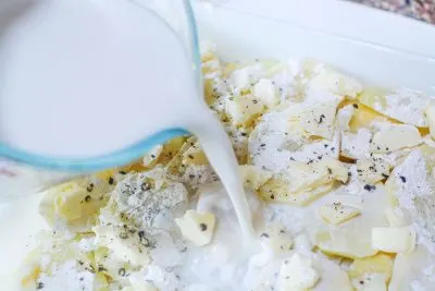 Pouring hot milk over scalloped potato Pouring hot milk over scalloped potato