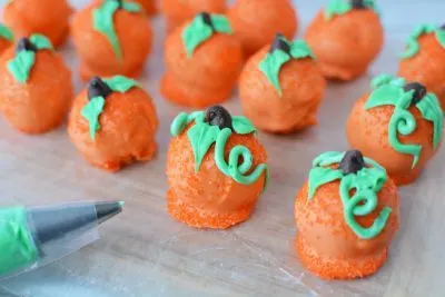 Adding stem and vine to pumpkin truffle with decorating tips