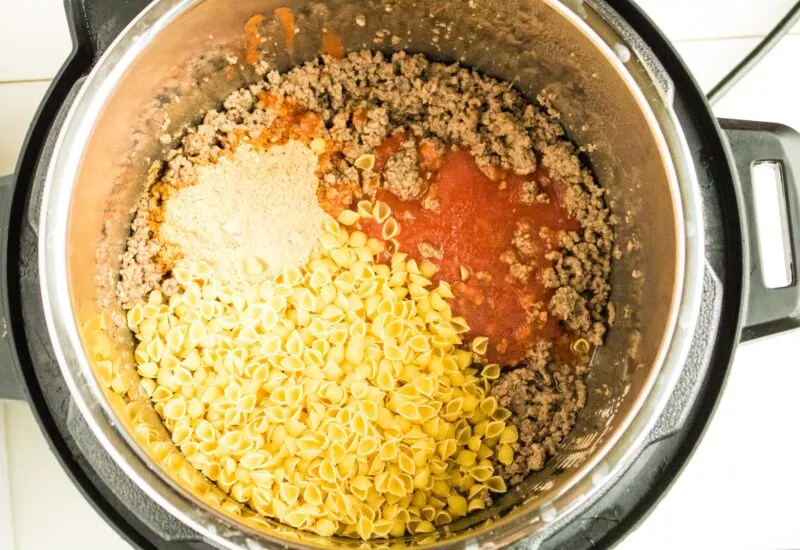 Adding shells and taco seasoning to the Instant Pot.