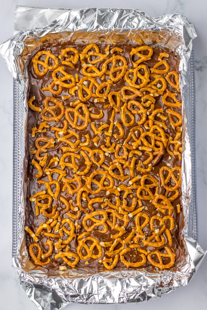 Adding the crushed pretzel on top of the dessert bars