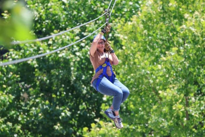 Woman hooked into a zipline across the Meramec River