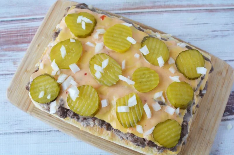 Adding pickles and onion to the burgers