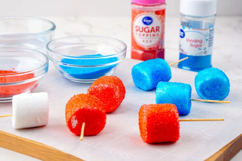 Dipping marshmallows into red and blue sanding sugar