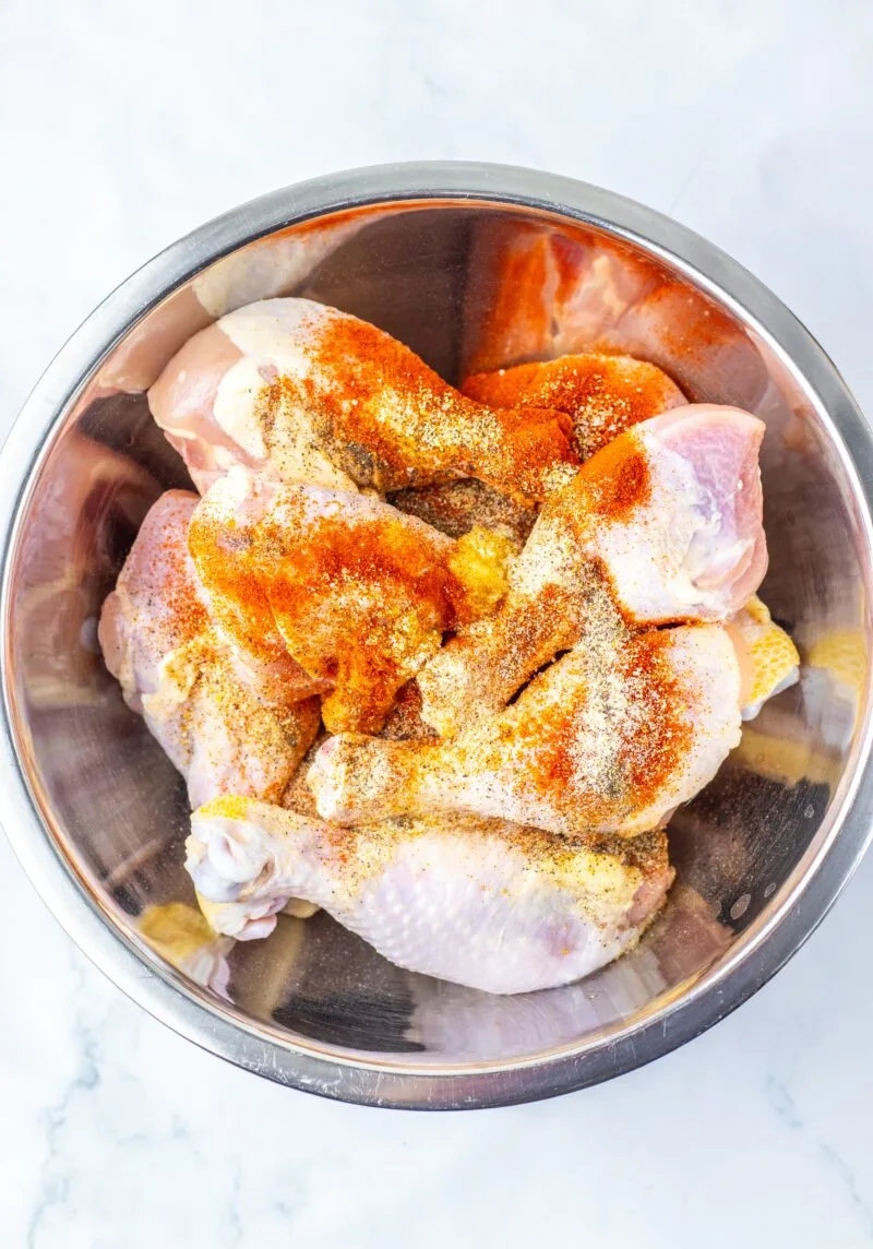 Adding the seasoning to the chicken legs in a bowl