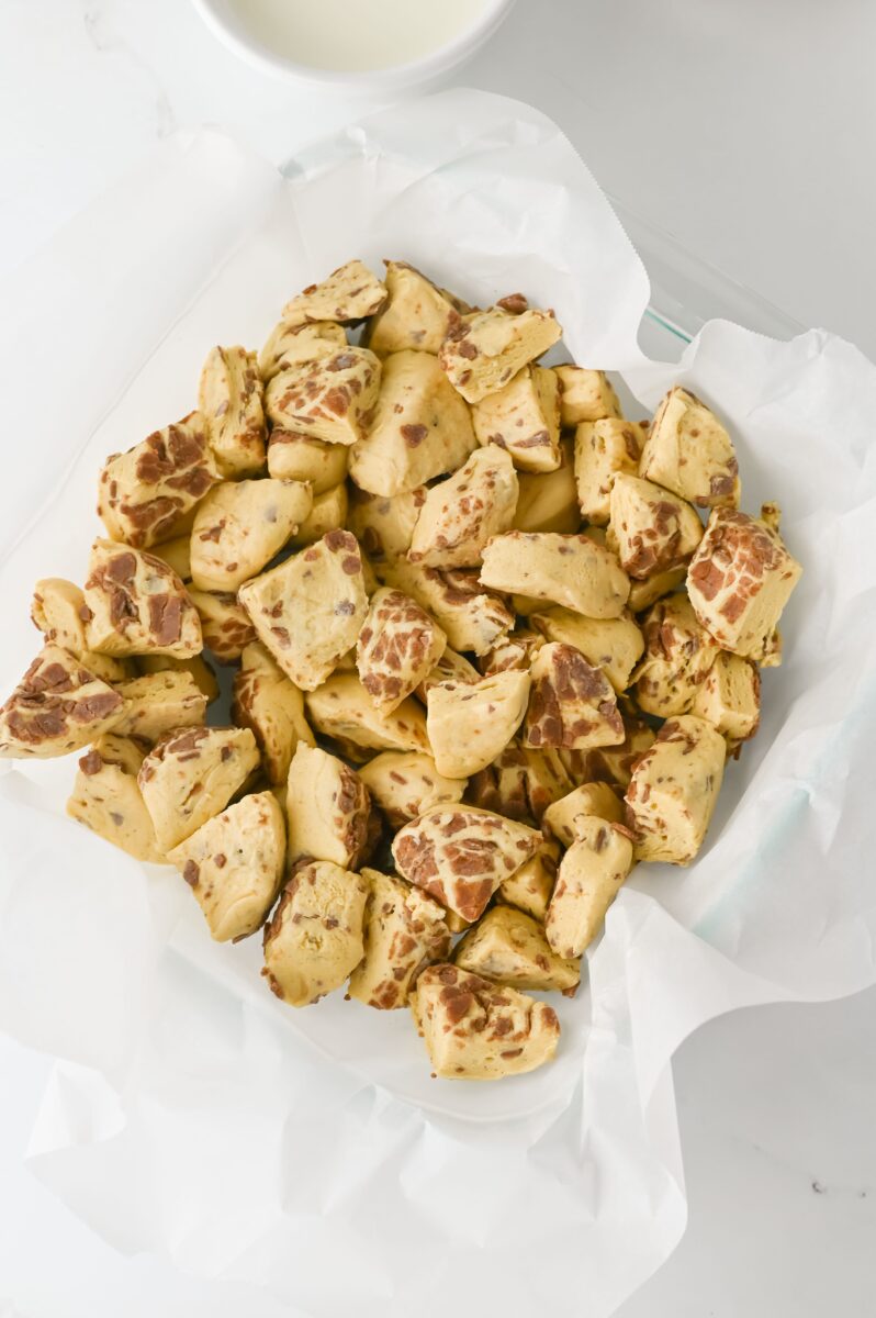 Adding the cubed cinnamon rolls to the casserole dish.