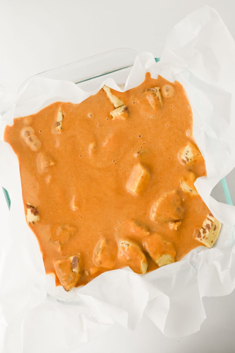 Pumpkin custard over the top of the cinnamon rolls, ready to bake.