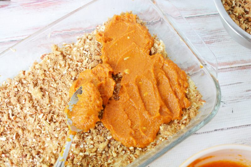 Spreading the pumpkin mixture over the top of the streusel.