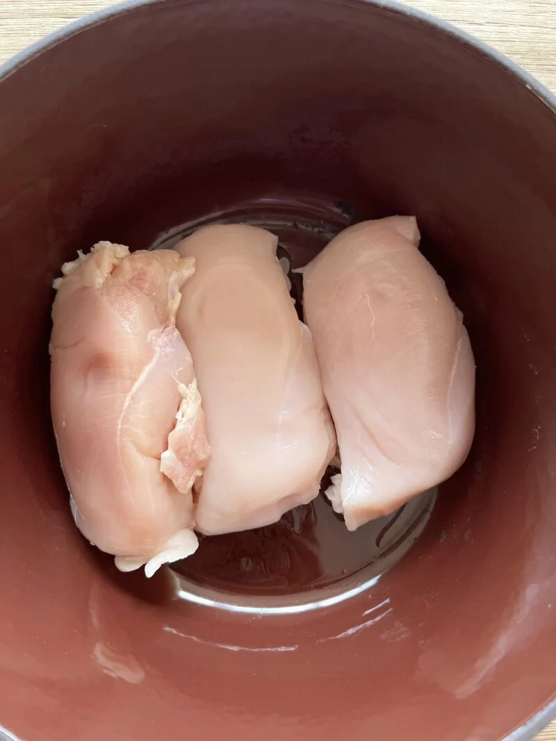 Adding chicken breasts to the stock pot