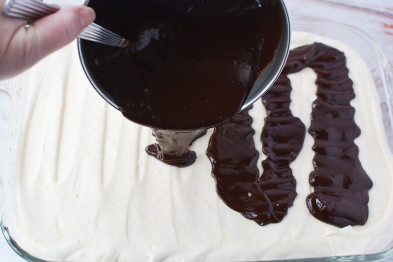 Pouring the ganache over the top of the Chocolate Eclair Cake