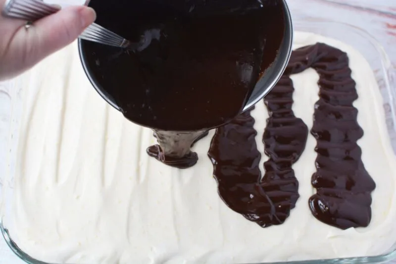 Pouring the ganache over the top of the Chocolate Eclair Cake