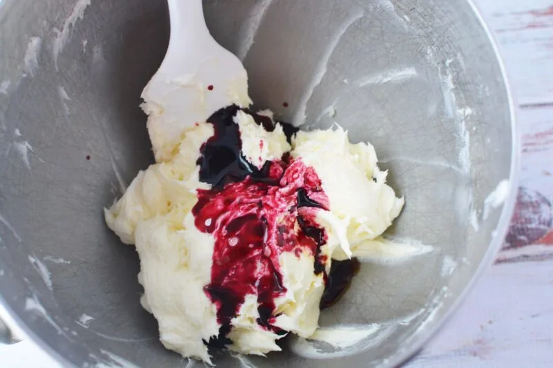 Adding the blueberry syrup to the frosting before mixing