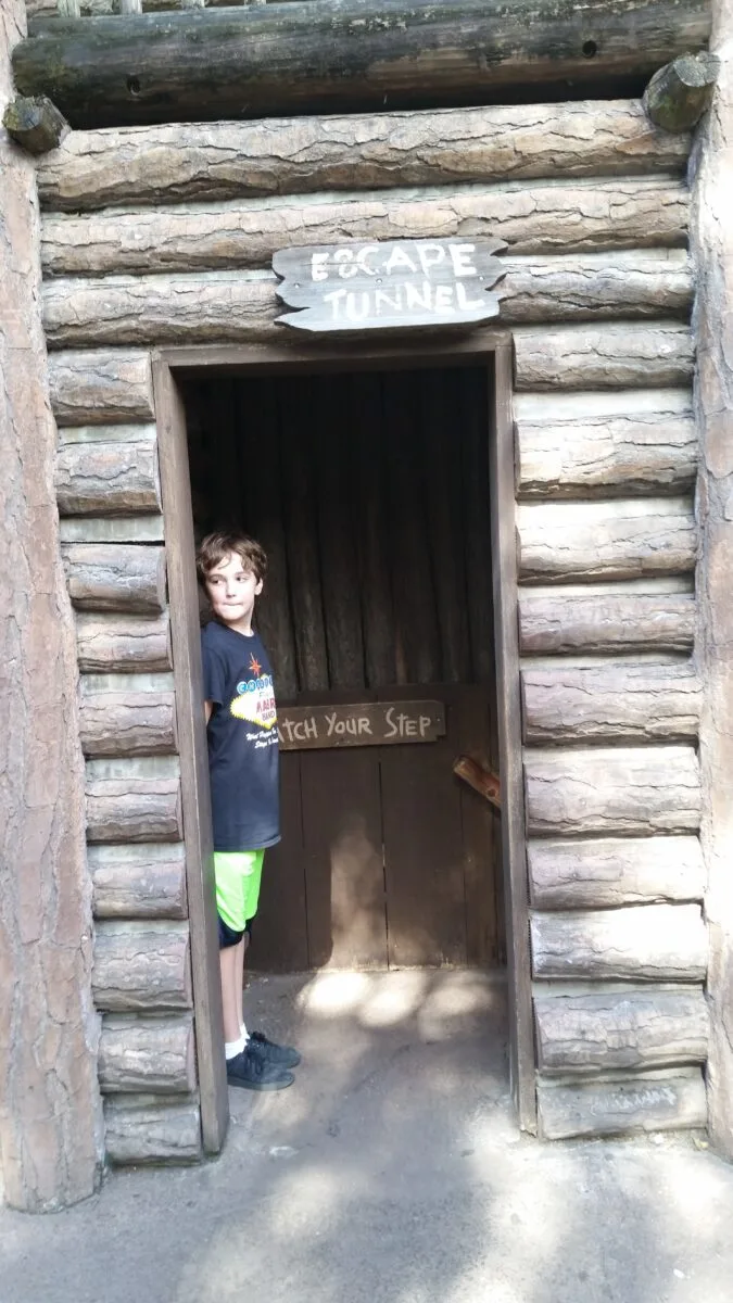 Young boy discovering a tunnel on Tom Sawyer Island in Walt Disney World.