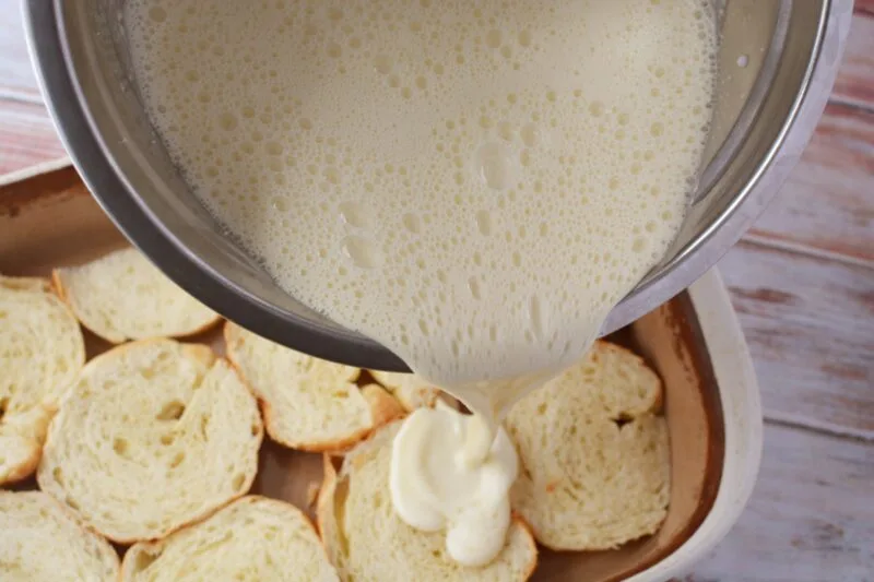 Pouring the custard onto the bottom layer of croissants