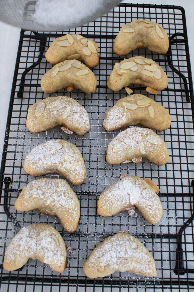 Adding powdered sugar on top of each almond crescent cookie