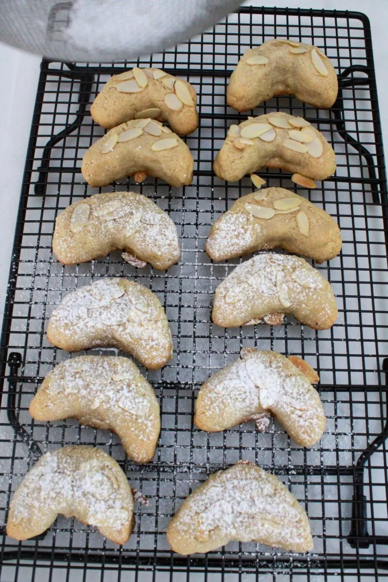 Adding powdered sugar on top of each almond crescent cookie