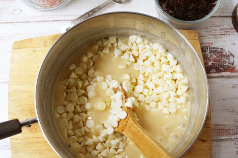 Adding the white chocolate chips into the saucepan.